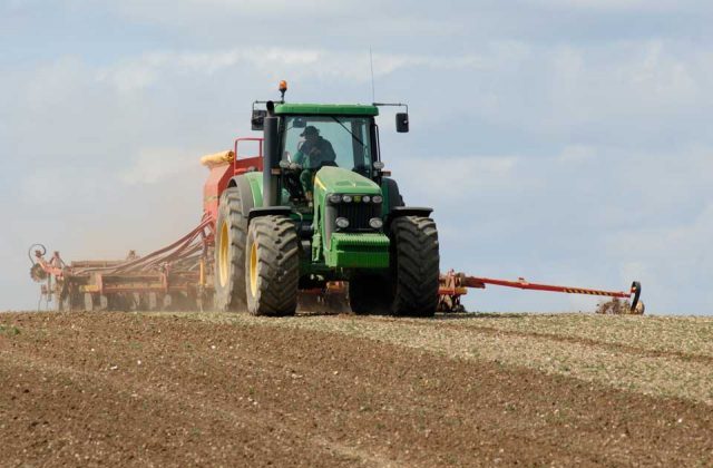 Image of a green tractor ploughing a field.