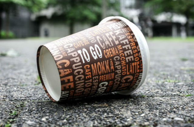 Photo of a discarded coffee cup on a concrete ground.