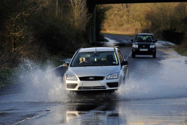 Image of a car driving through a flood.