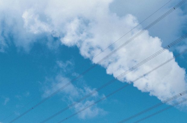 Telephone lines against clouds and a blue sky.