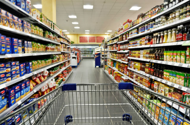 An image of a shopping trolley being pushed down a supermarket aisle.