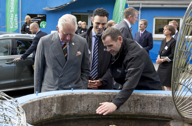 An image of Prince Charles talking to staff next to a pond.