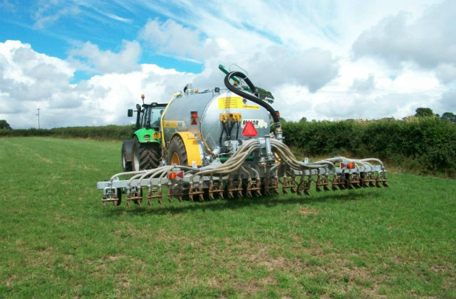 An image of agricultural machinery in a green field against a blue sky.