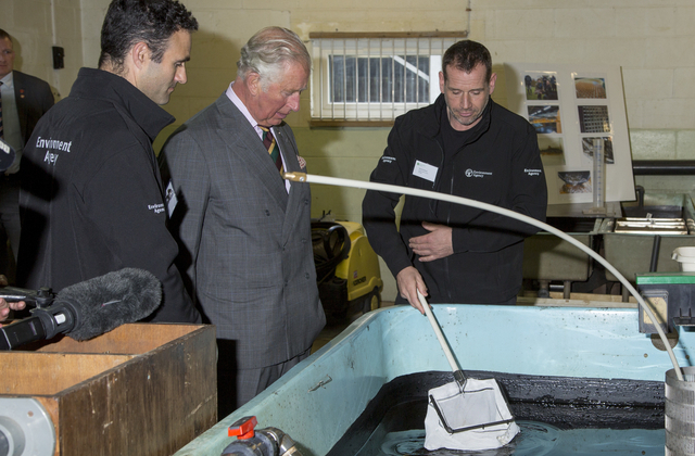 An image of Prince Charles being shown a demonstration by staff at the salmon centre