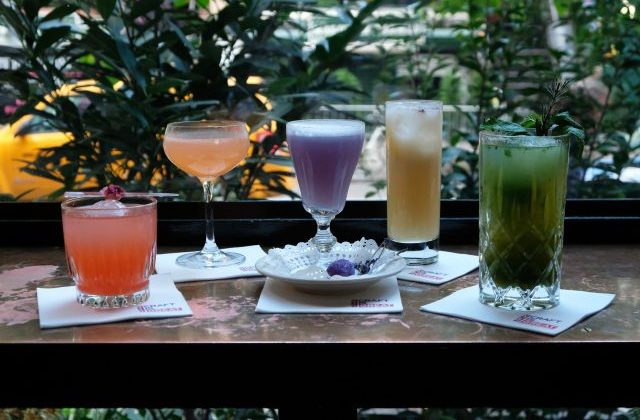 An image of different coloured cocktails on a wood table.