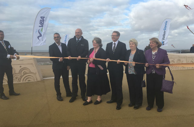 Image of Minister Coffey at the flood defence opening cutting the ribbon surrounded by 5 other people.