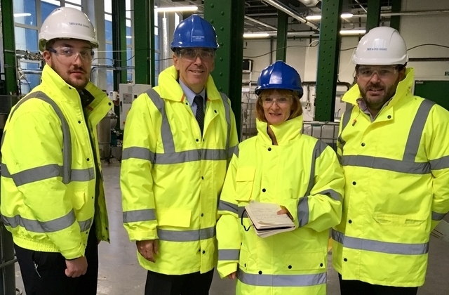 Minister Rutley in a high vis jacket and a helmet standing at the Tate and Lyle factory surrounded by three other people.