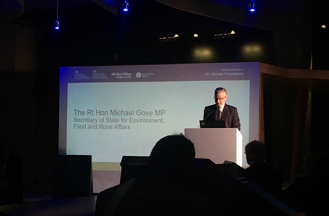 An image of nvironment Secretary Michael Gove speaking on stage at the launch of the UKCCP. The presentation behind him says 'The Rt Hon Michael Gove MP, Secretary of State for Enviroment, Food and Rural Affairs'.