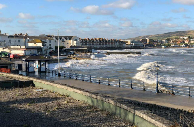 An image of a harbour with waves breaking against the shore.