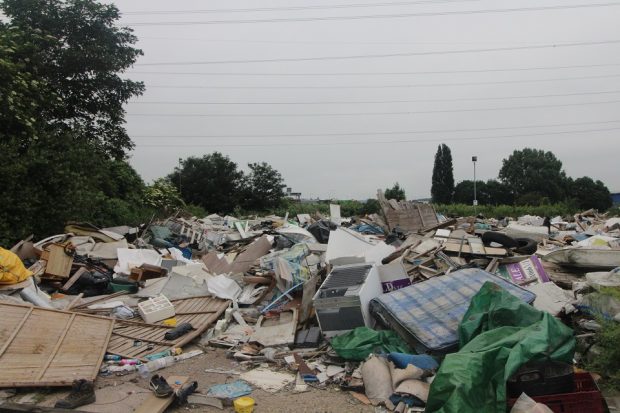 Image of waste in a dump against a gray sky.