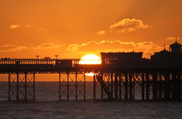 Image of a sunset behind a pier on a beach