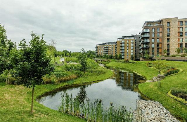 Image of a building development in Kidbrooke, with a lake and greenery surrounding it.