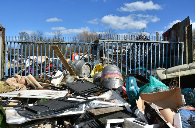 An image of discarded waste against a gate. 