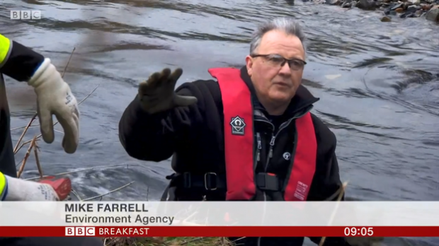 Mike Farrell from the Environment Agency speaking on BBC Breakfast wearing a red vest against a backdrop of water