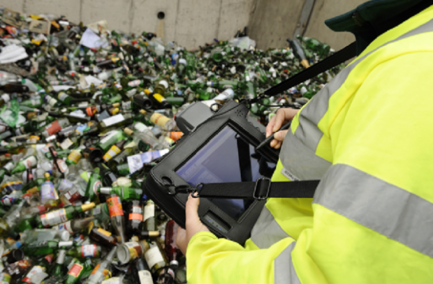 Image of a woman with a screen looking at a pile of glass bottles.