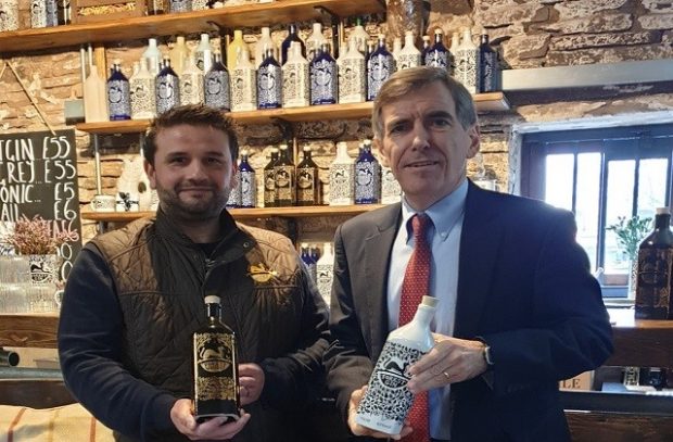 Minister Rutley standing next to a member of Forest Distillery holding a bottle of gin.
