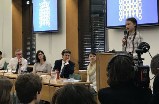 • Picture of Greta Thunberg speaking behind a podium and a panel comprised of Environment Secretary Michael Gove, and MPs Layla Moran, Ed Miliband and Caroline Lucas.