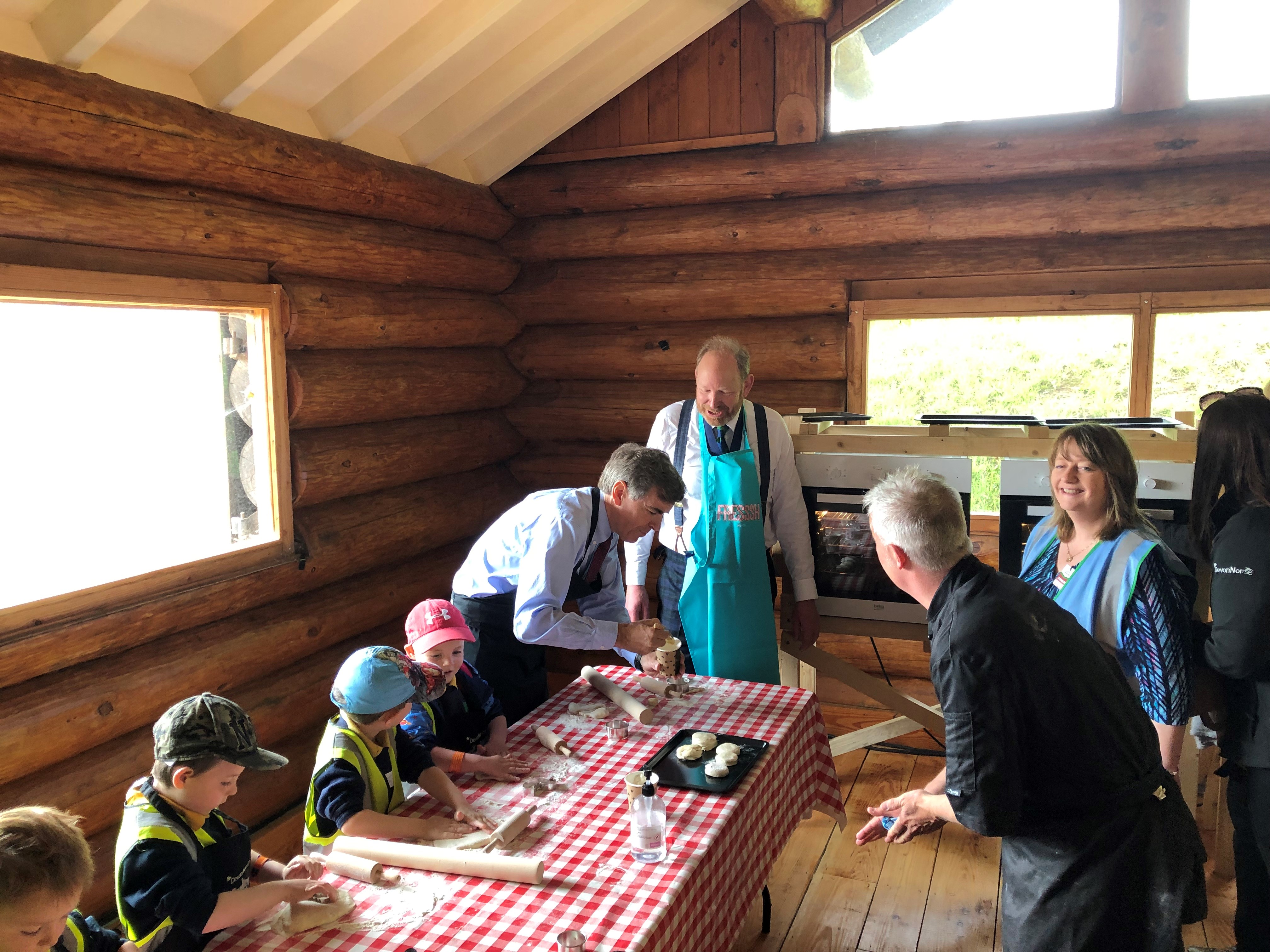 image of minister Rutley and sit Harry Studholme making scones with school children. 