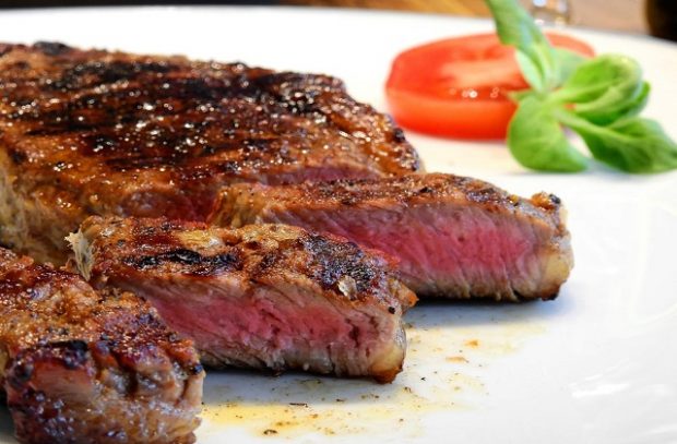 An image of a sliced steak on a plate with lettuce and tomato.