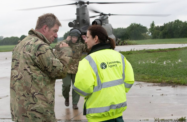 EA staff standing on the ground next to an RAF member and a Chinook helicopter