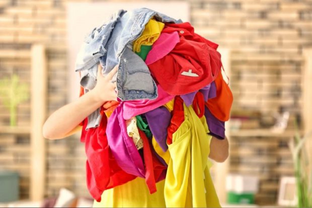 A woman holding a bundle of brightly coloured clothes