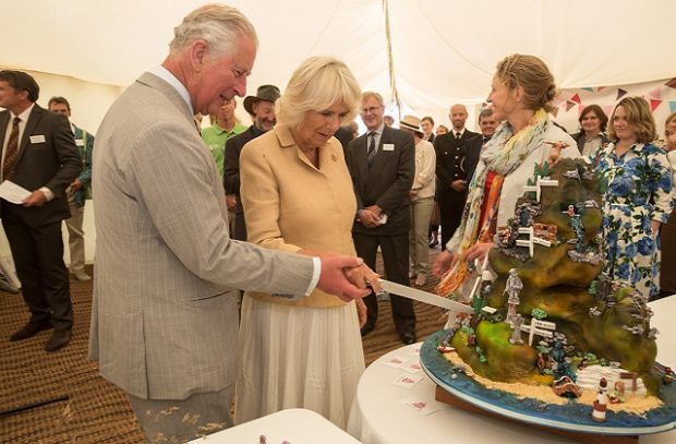 An image of HRH Prince Charles and the Duchess of Cornwall cutting a cake.