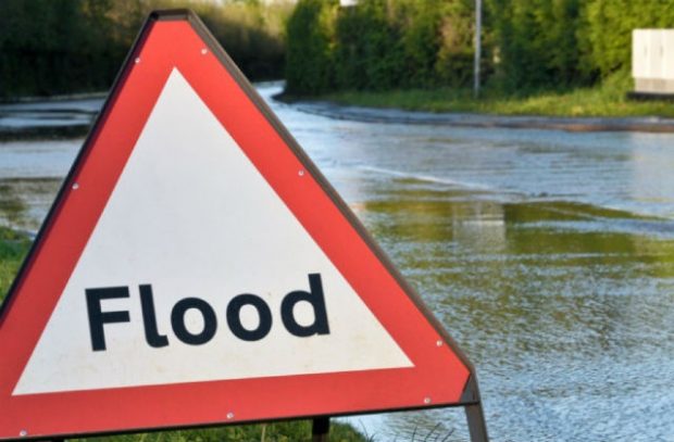 Image of a flood sign against a flooded backdrop.