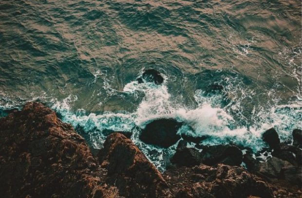 Water lapping at rocks at the base of a cliff