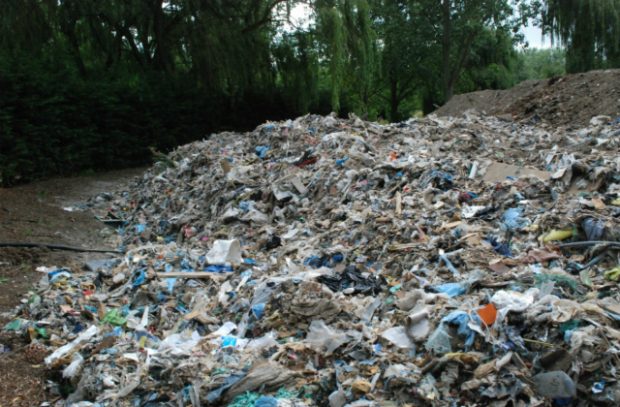 A picture showing tonnes of mixed waste that has been dumped on private rural land