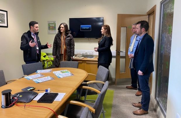 Environment Secretary Theresa Villiers in a room with four Environment Agency staff members standing in front of a table with paper documents on