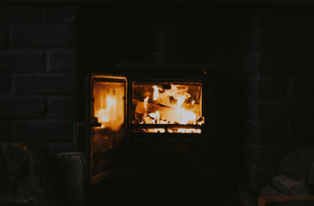 several wooden logs burning in a stove inside a brick fireplace