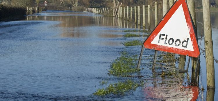 A flood warning sign, on a closed country road next to water logged fields in the Avon Valley, Hampshire, England. Flooded after an extreme amount of rainfall at the start of 2014