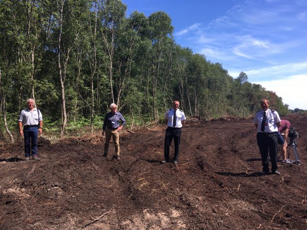 Tony Juniper, Damian Allen from Doncaster Council, and two men from South Yorkshire Fire and Rescue Service stand in a field at the Hatfield Moor site