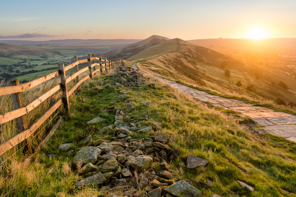 A stone footpath and wooden fence leading along the Great Ridge in the Peak District.